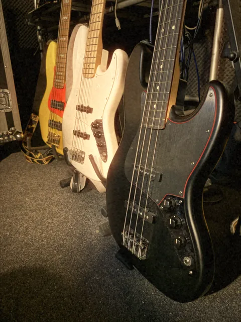 Three bass guitars on stands in the studio