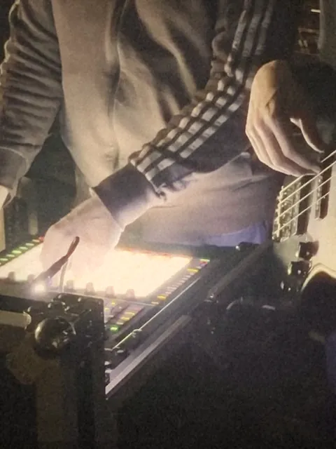 Hands on glowing Push pads next to a bass guitar